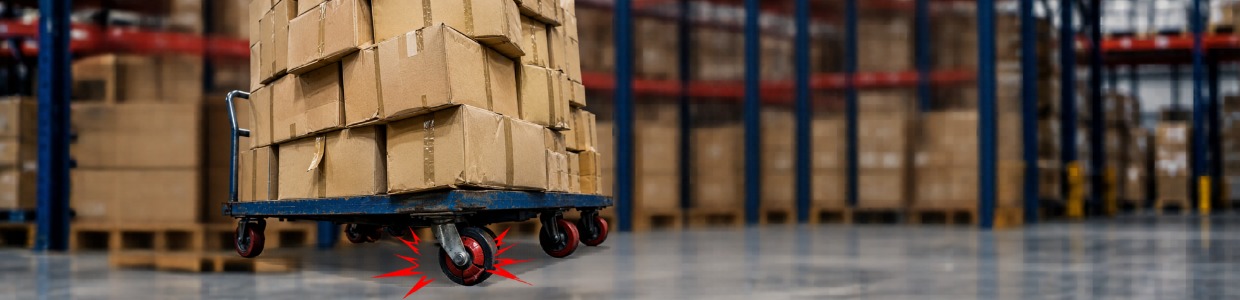 Overloaded platform trolley carrying stacked cartons in a warehouse, showing stress on industrial castor wheels due to excessive load capacity | Rexello Castors